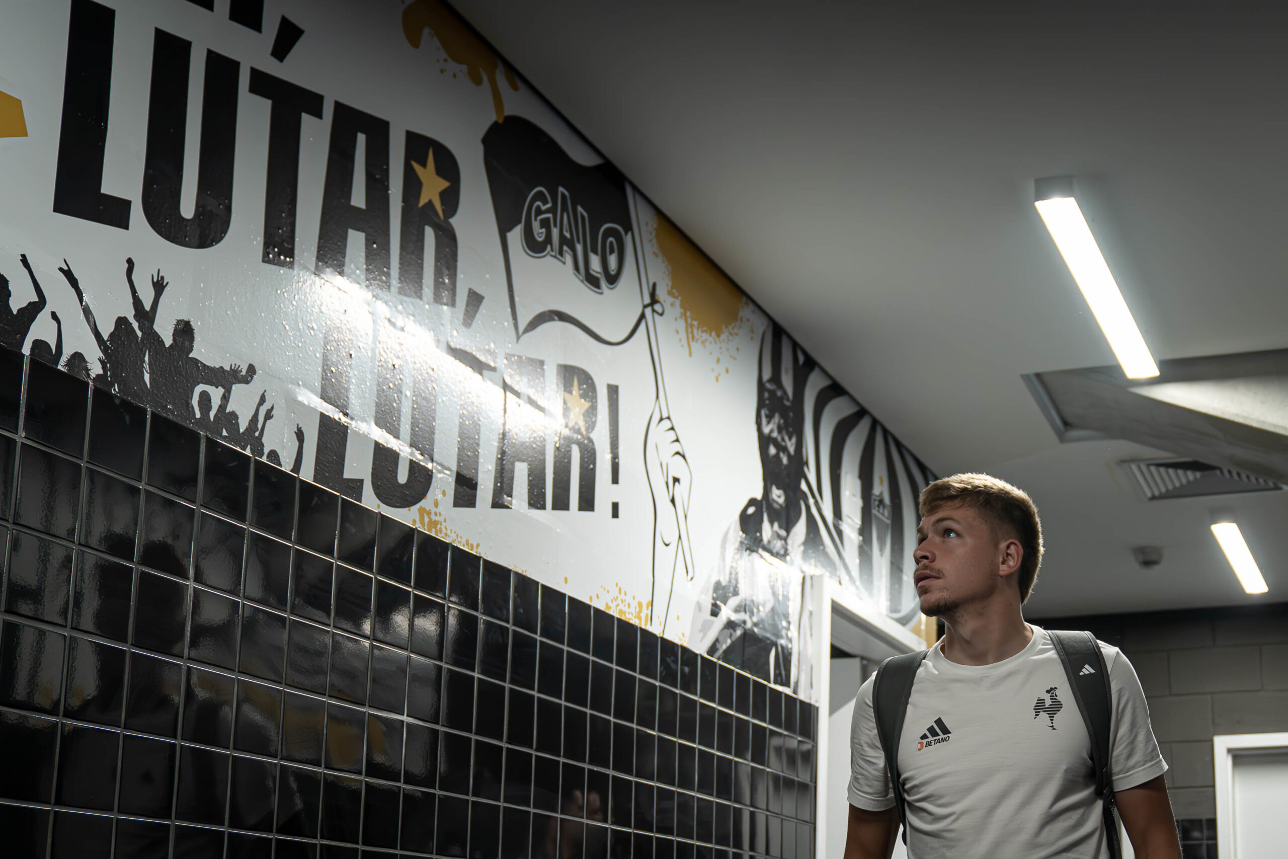 Bruno Fuchs lê trecho do hino estampado nos corredores da Arena MRV – Foto: Pedro Souza / Atlético